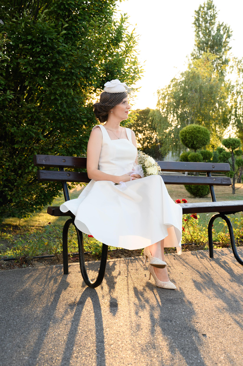 Mlada sedi na klupi na Kalemegdanu u Beogradu, zagledana u daljinu – umetnička fotografija venčanja by MI Weddings