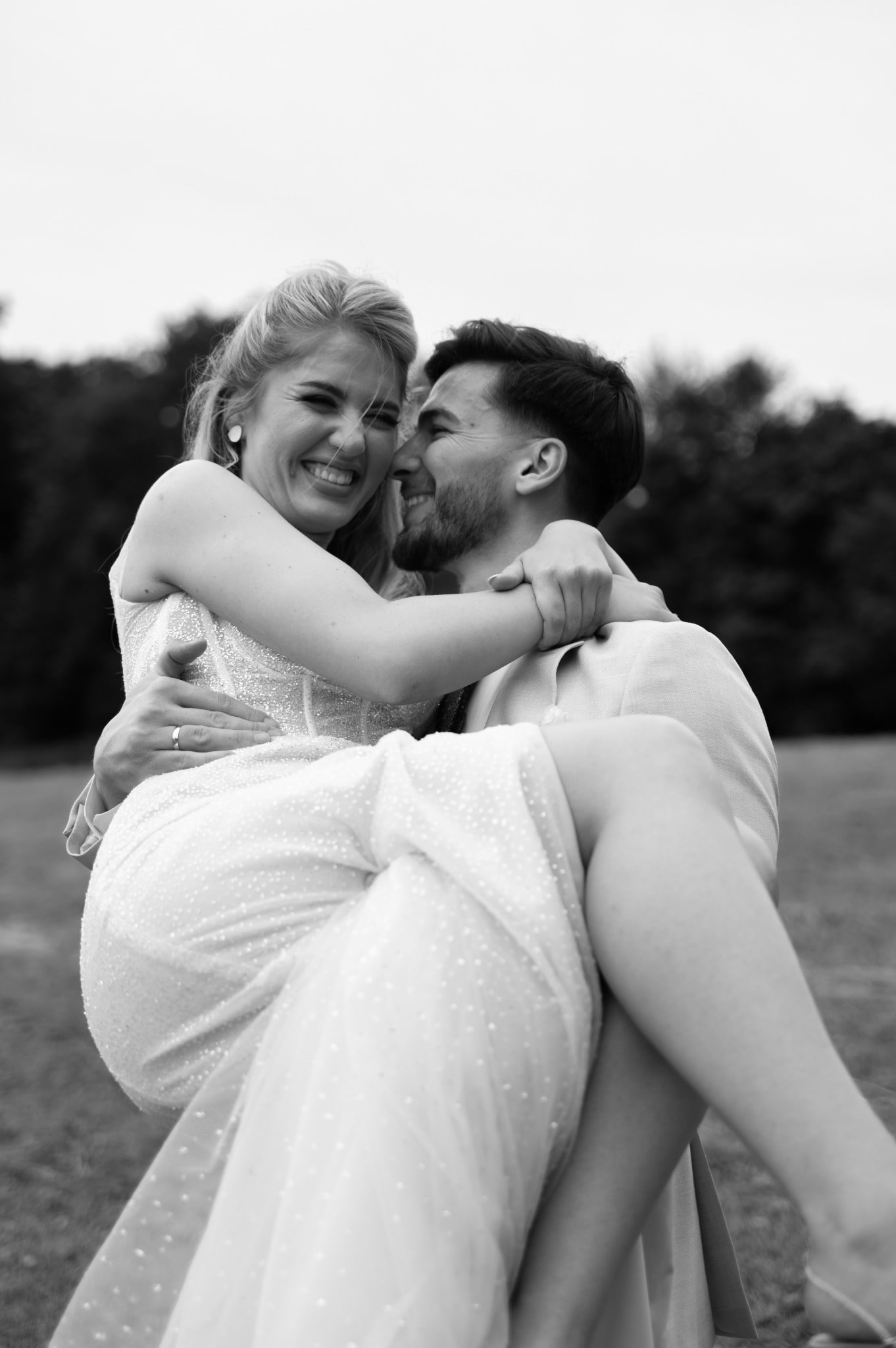 Crno-bela umetnička fotografija mladoženje koji nosi mladu na Kalemegdanskoj terasi u Beogradu